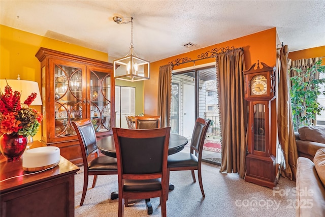 dining area featuring light carpet, plenty of natural light, and a textured ceiling