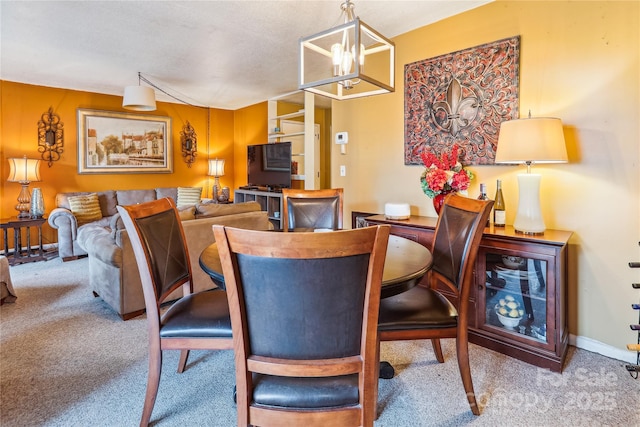 carpeted dining space featuring baseboards and an inviting chandelier