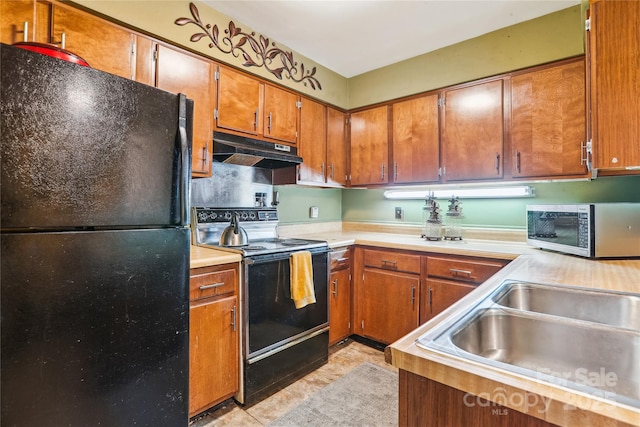 kitchen featuring brown cabinets, light countertops, a sink, under cabinet range hood, and black appliances