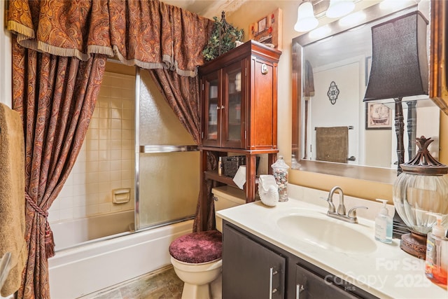 full bath with vanity, toilet, and bath / shower combo with glass door