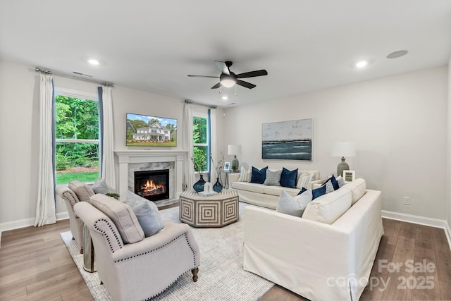 living room with a high end fireplace, baseboards, recessed lighting, wood finished floors, and a ceiling fan