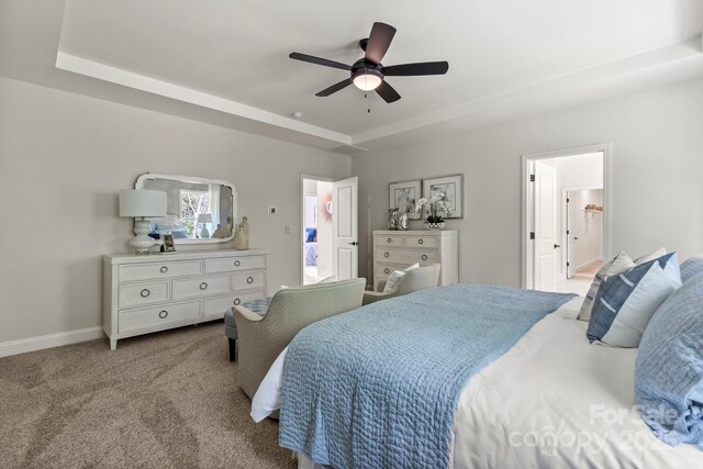 carpeted bedroom featuring a raised ceiling, a ceiling fan, and baseboards