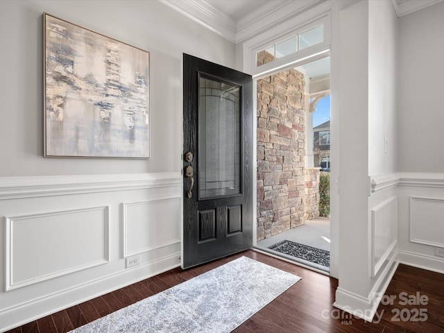 entryway with dark wood-style floors, a decorative wall, crown molding, and a wainscoted wall