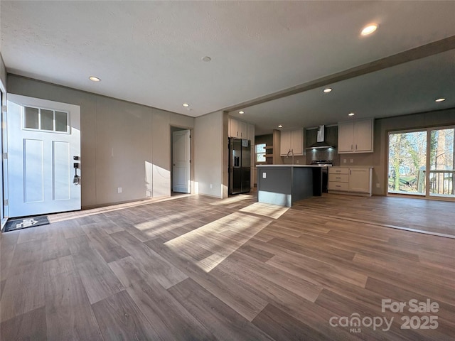 unfurnished living room featuring a sink, recessed lighting, and wood finished floors