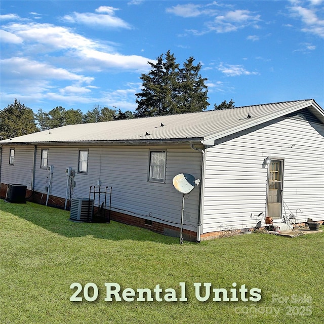 back of property featuring crawl space, central AC, a yard, and metal roof