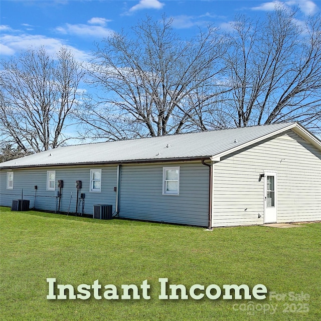 rear view of house featuring metal roof, a yard, and central AC