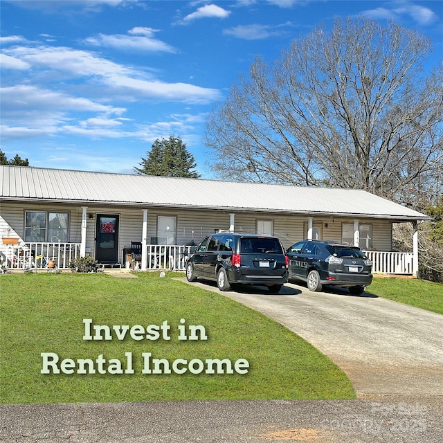 ranch-style home featuring covered porch, metal roof, a front yard, and driveway