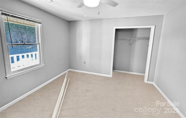 unfurnished bedroom featuring a closet, multiple windows, a textured ceiling, and baseboards