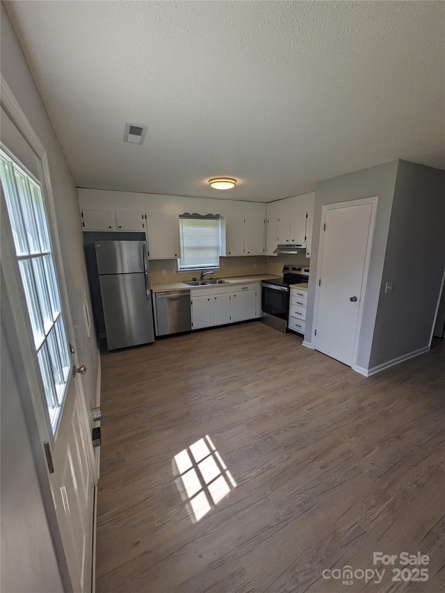 kitchen with visible vents, dark wood finished floors, stainless steel appliances, under cabinet range hood, and a sink