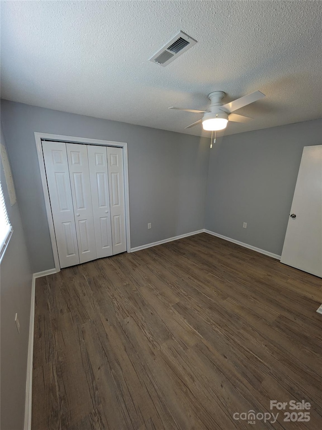 unfurnished bedroom with visible vents, dark wood finished floors, baseboards, and ceiling fan