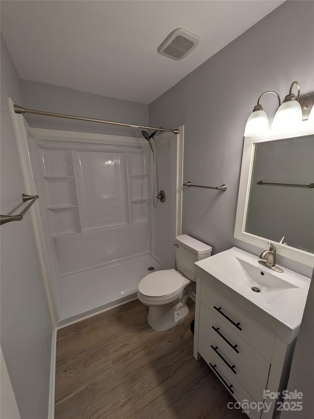 full bath featuring toilet, wood finished floors, visible vents, vanity, and walk in shower