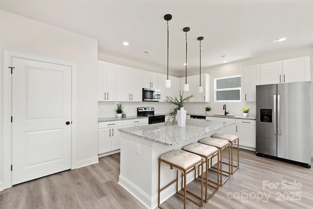 kitchen featuring light stone countertops, white cabinetry, stainless steel appliances, and a center island