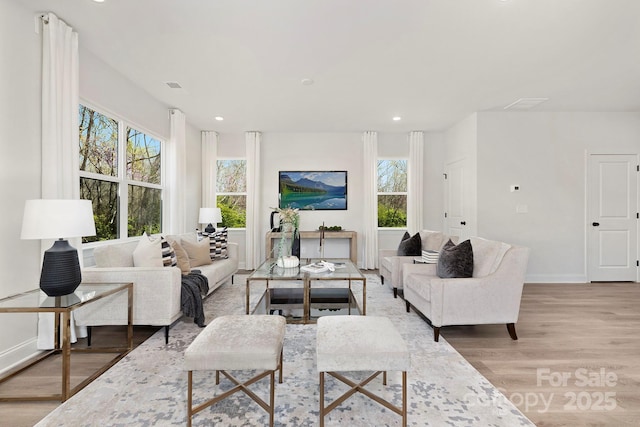 living room featuring light wood-style floors, visible vents, baseboards, and recessed lighting