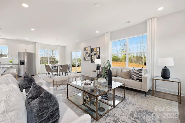 living room with light wood-style floors, recessed lighting, and baseboards