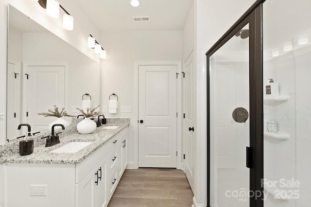 bathroom with double vanity, visible vents, a sink, and wood finished floors