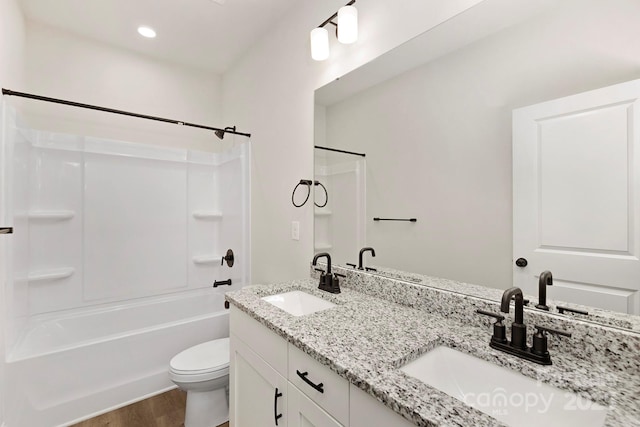 bathroom featuring washtub / shower combination, a sink, toilet, and wood finished floors