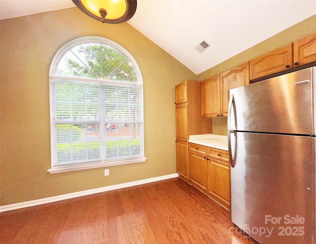 kitchen featuring lofted ceiling, visible vents, light countertops, freestanding refrigerator, and wood finished floors