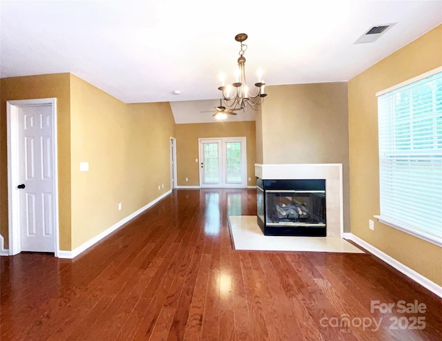 unfurnished living room featuring visible vents, a multi sided fireplace, wood finished floors, a chandelier, and baseboards