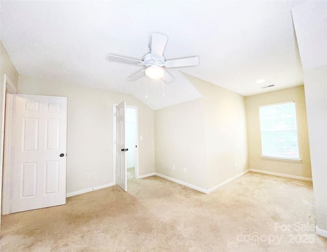 empty room with light carpet, visible vents, baseboards, ceiling fan, and vaulted ceiling