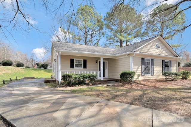 single story home featuring concrete driveway, a porch, and a front lawn