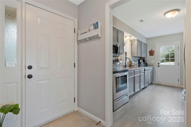 kitchen with open shelves, gray cabinets, light countertops, visible vents, and appliances with stainless steel finishes