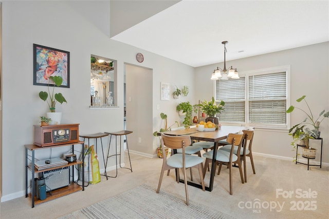 dining space featuring light colored carpet, baseboards, and an inviting chandelier