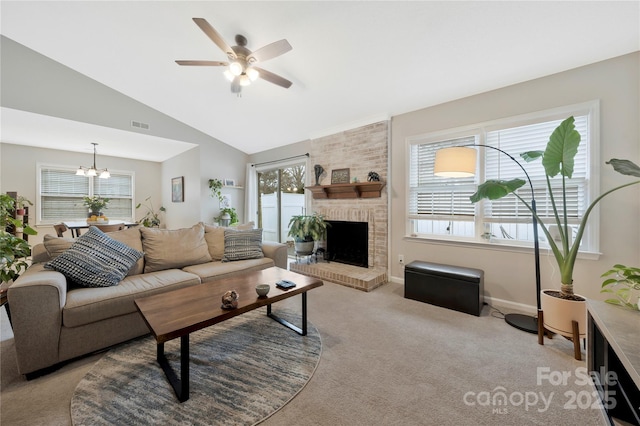 living area with light colored carpet, ceiling fan with notable chandelier, a fireplace, visible vents, and vaulted ceiling