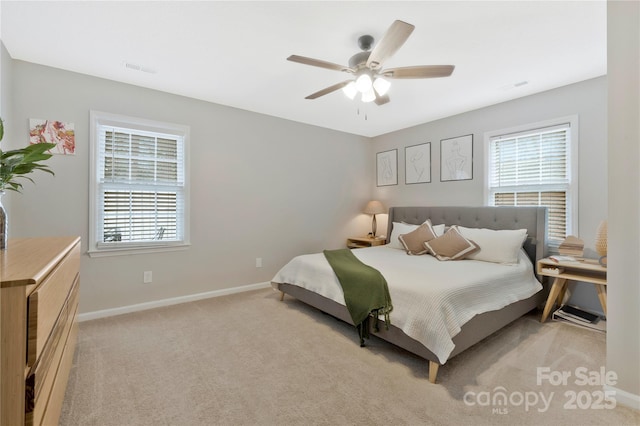 bedroom with light carpet, multiple windows, baseboards, and a ceiling fan