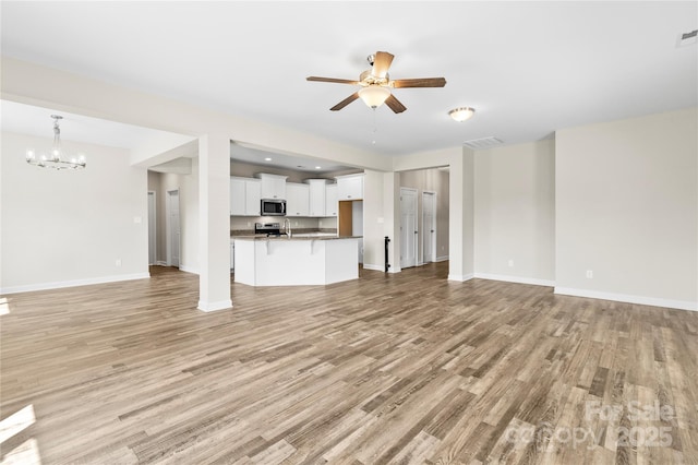 2504 Hovis Rd, Lincolnton, NC 28092 - unfurnished living room featuring ceiling fan, light wood-type flooring, a chandelier, and baseboards