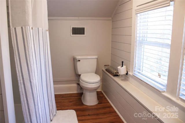 bathroom featuring wooden walls, visible vents, toilet, wood finished floors, and vaulted ceiling