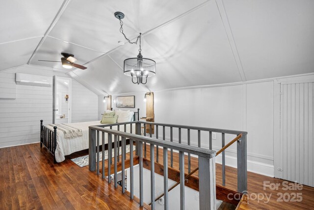 interior space featuring a wall unit AC, wood-type flooring, and vaulted ceiling