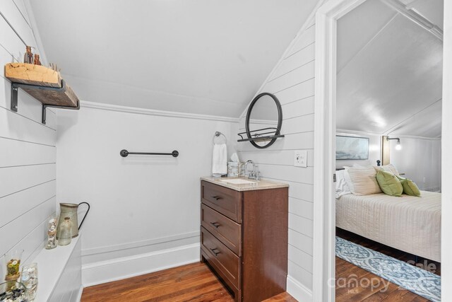 ensuite bathroom with vaulted ceiling, ensuite bath, wood finished floors, and vanity