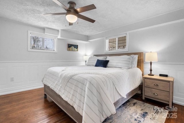 bedroom featuring a wainscoted wall, a textured ceiling, a ceiling fan, and wood finished floors