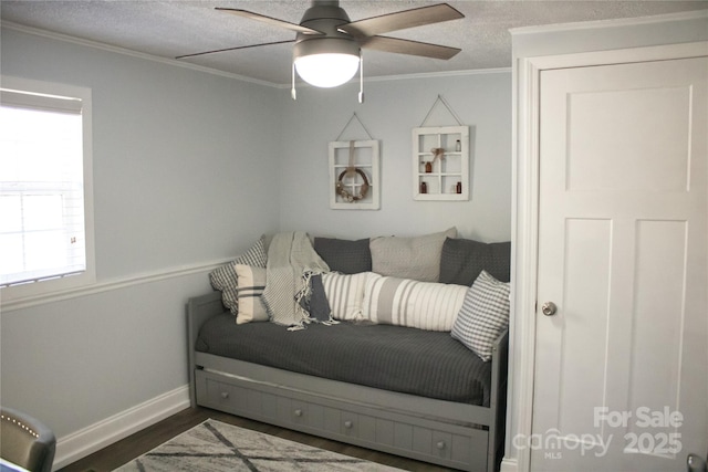 sitting room with baseboards, ceiling fan, ornamental molding, wood finished floors, and a textured ceiling