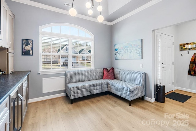 sitting room with ornamental molding, light wood-type flooring, visible vents, and baseboards