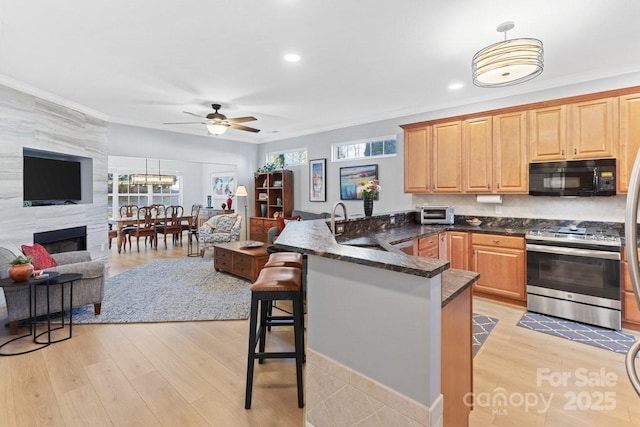 kitchen featuring open floor plan, stainless steel range oven, a kitchen bar, and black microwave