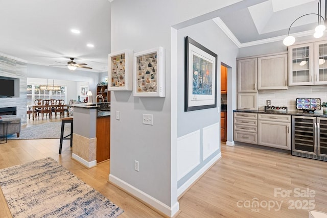 kitchen with beverage cooler, dark countertops, glass insert cabinets, open floor plan, and decorative light fixtures