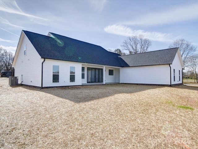 rear view of property featuring central AC unit and roof with shingles