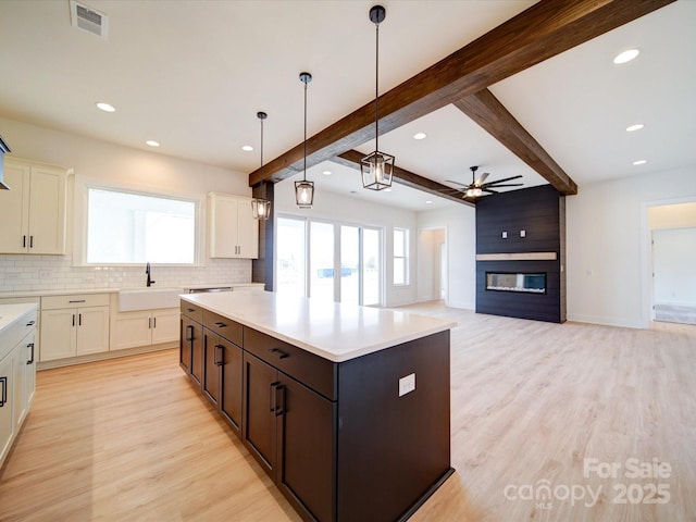 kitchen featuring open floor plan, light countertops, a sink, and a center island