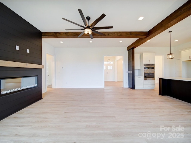 unfurnished living room featuring light wood-type flooring, beam ceiling, a fireplace, and recessed lighting