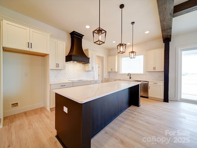 kitchen with dishwasher, custom range hood, a kitchen island, light wood-style floors, and pendant lighting