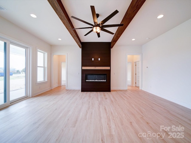 unfurnished living room with light wood-type flooring, a large fireplace, baseboards, and beamed ceiling