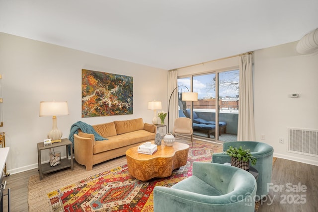 living room featuring baseboards, visible vents, and wood finished floors