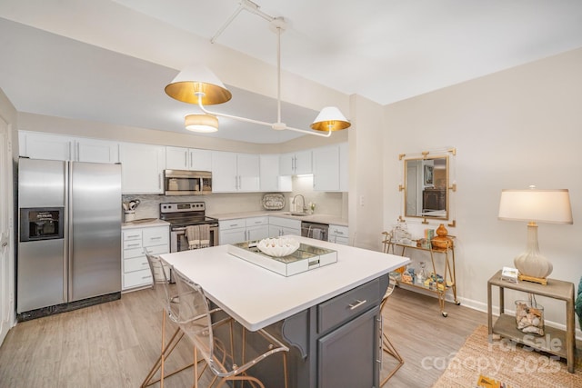 kitchen with appliances with stainless steel finishes, light countertops, white cabinets, and a sink