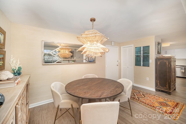 dining space with a chandelier, light wood-type flooring, and baseboards