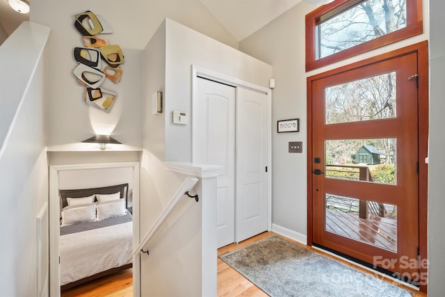 foyer entrance with light wood finished floors and vaulted ceiling