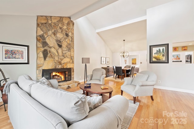 living area featuring a fireplace, light wood finished floors, high vaulted ceiling, beamed ceiling, and baseboards