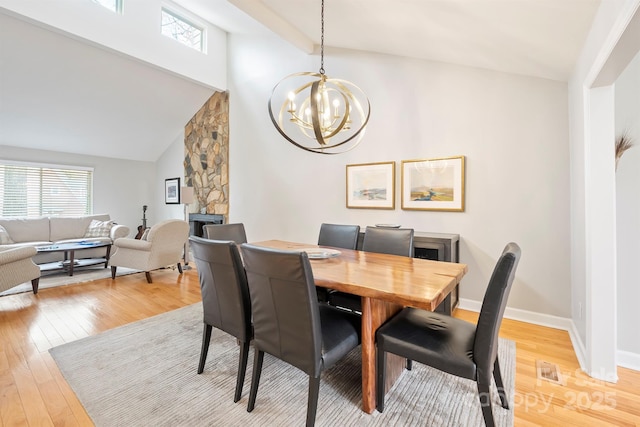 dining room with light wood-type flooring, a wealth of natural light, a chandelier, and baseboards