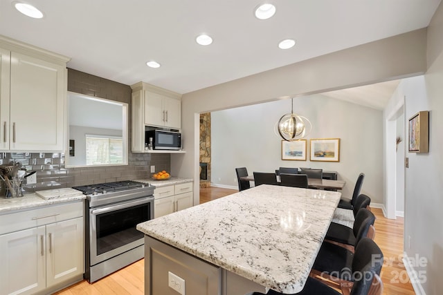 kitchen with tasteful backsplash, a kitchen island, light stone counters, a breakfast bar, and gas stove