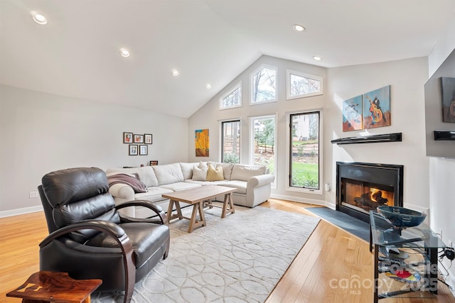 living area with baseboards, a fireplace with flush hearth, wood finished floors, high vaulted ceiling, and recessed lighting